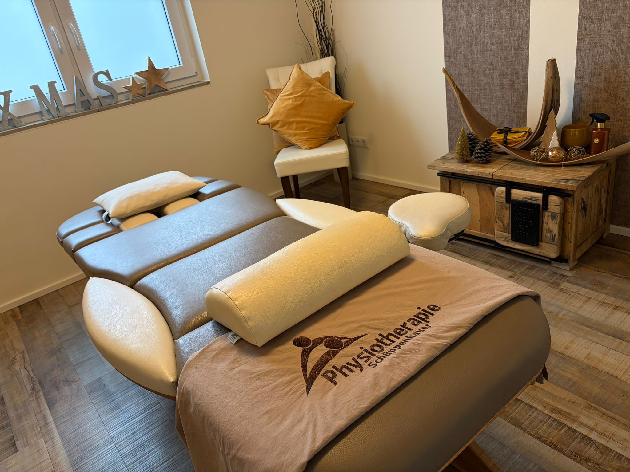 Behandlungsraum mit Massageliege und Physiotherapie Schüppenhauer Logo